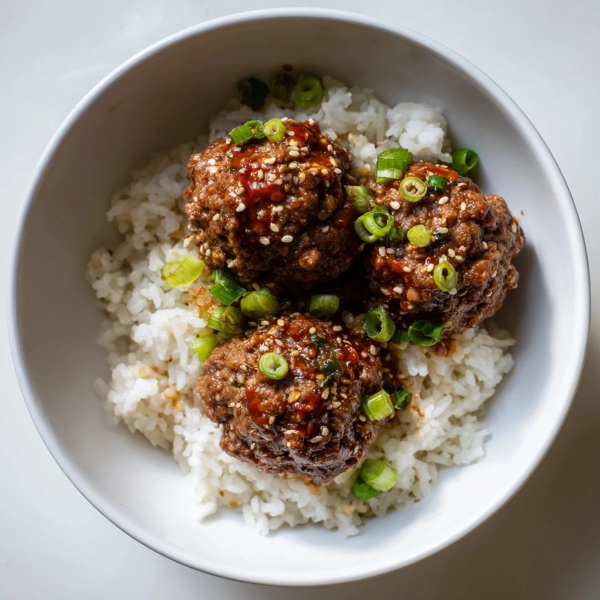 A close-up of delicious Spicy Sriracha Beef Meatballs glistening with a flavorful, rich sauce.