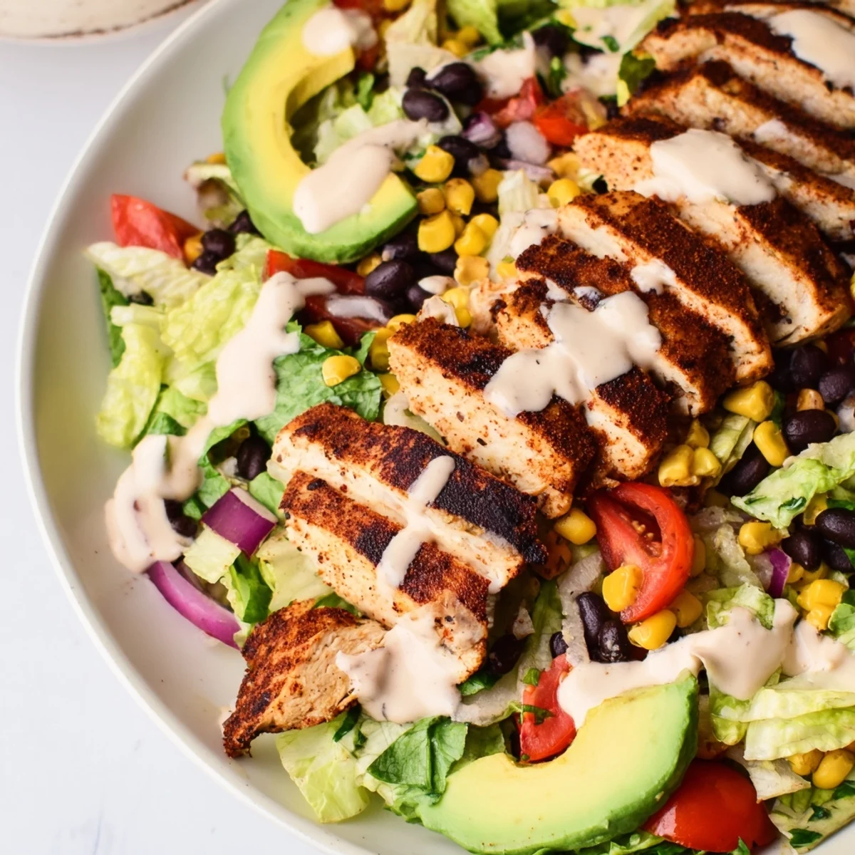 Sliced grilled chicken crowns a hearty Southwest Chicken Salad, garnished with fresh cilantro and served with a side of zesty chipotle lime dressing.