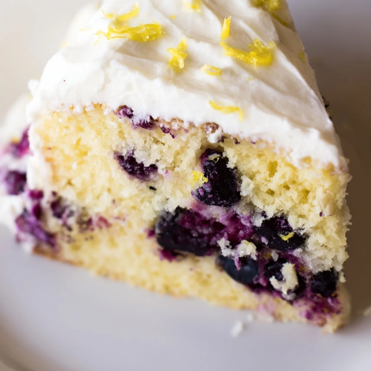 A rustic Lemon Blueberry Cake is plated with a fork, ready to serve at a sunny brunch table near a glass of milk.