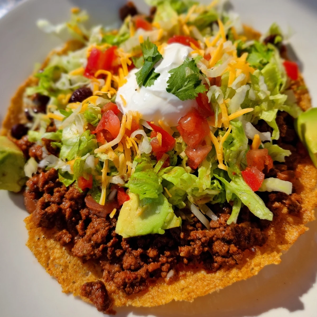 Colorful platter of Mexican-style Beef Tostadas topped with avocado slices and a squeeze of lime.