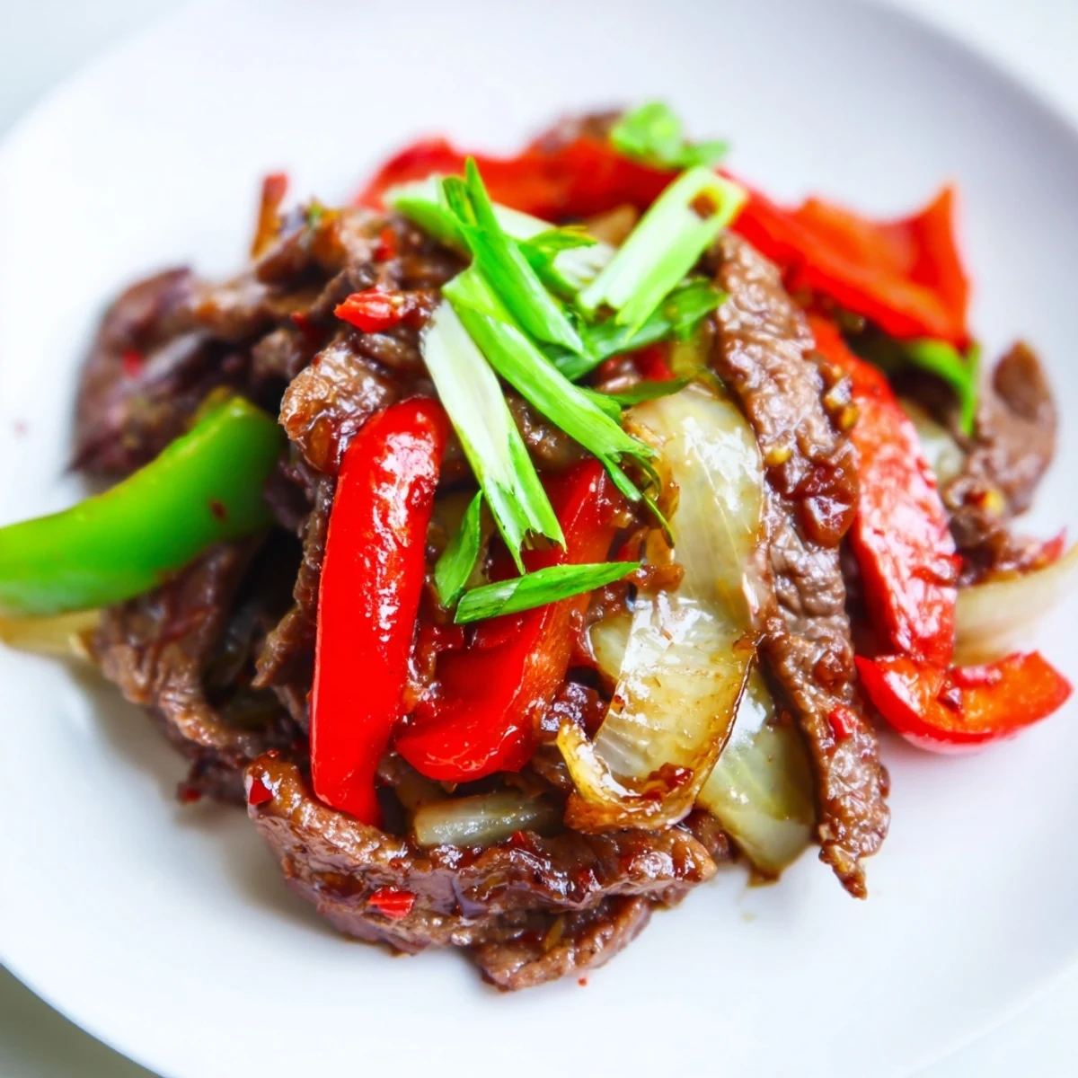 Tender strips of beef and crisp bell peppers glisten in a spicy stir fry beef sauce.