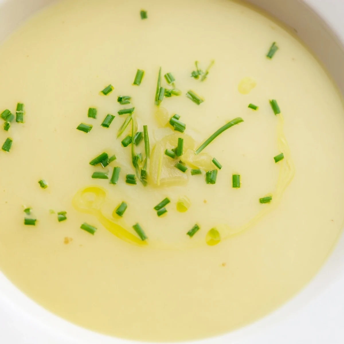 A warm bowl of Irish Potato Leek Soup with Chives, garnished with fresh herbs.  