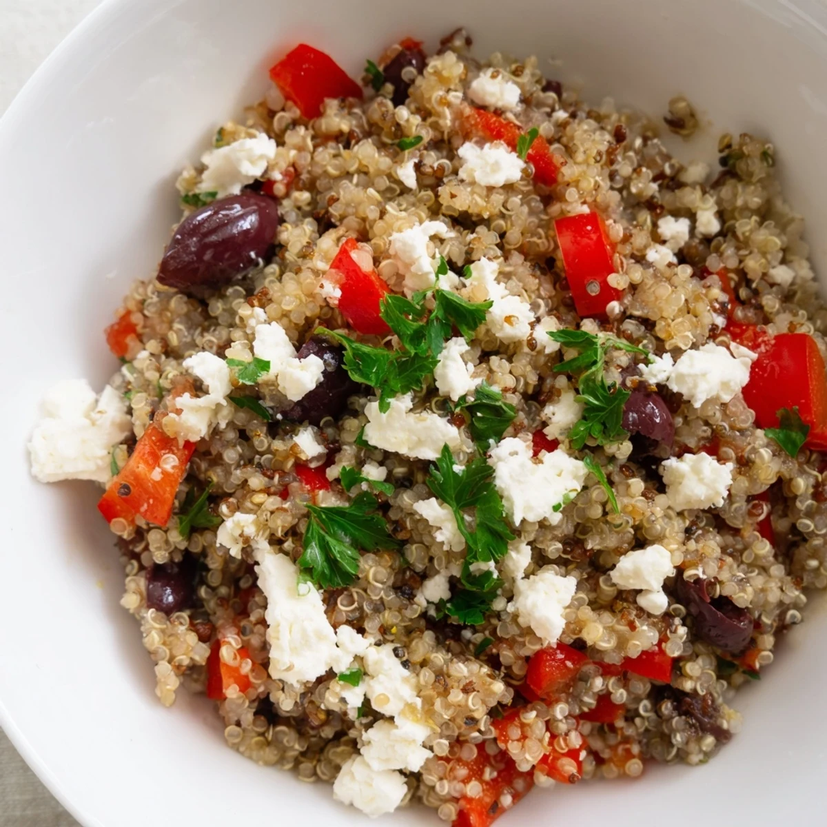 Vibrant Mediterranean Quinoa Salad with feta, olives, and crisp vegetables served in a white bowl.