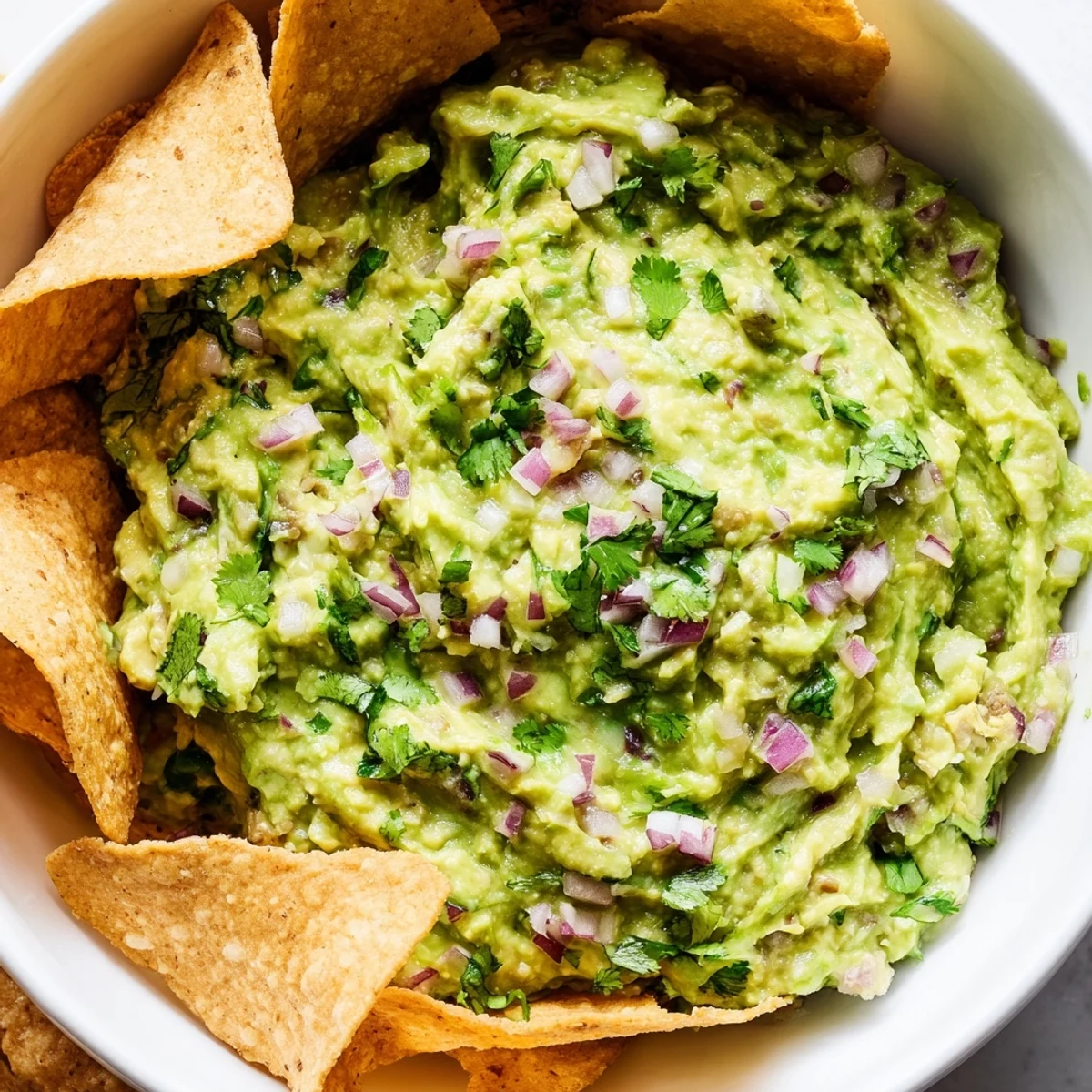 A festive platter of Game Day Spicy Guacamole with Tortilla Chips, ready for a crowd, featuring jalapeño slices and a zesty lime garnish.