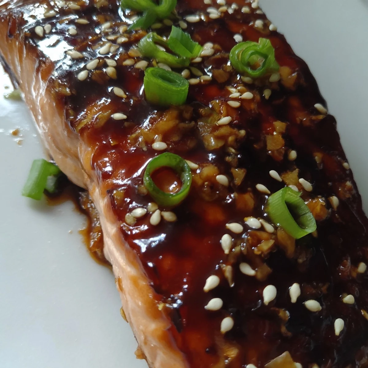 Glossy baked salmon fillets drenched in homemade teriyaki glaze, garnished with sesame seeds and fresh green onions for a savory-sweet dinner.