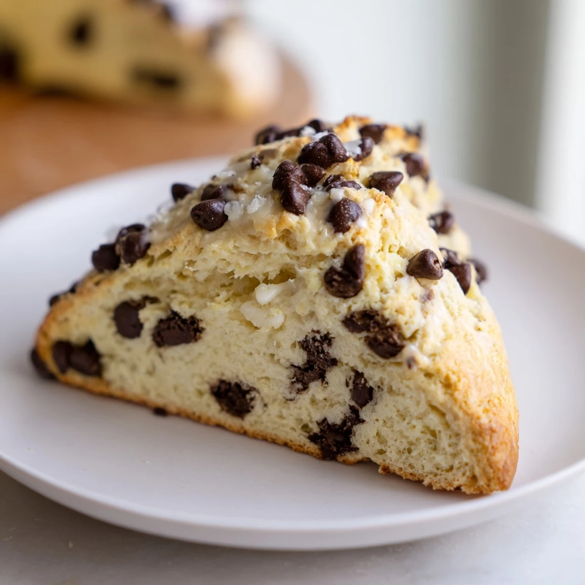 Freshly baked Chocolate Chip Scones cooling on a wire rack, showing a golden crust and visible melty chocolate chunks.