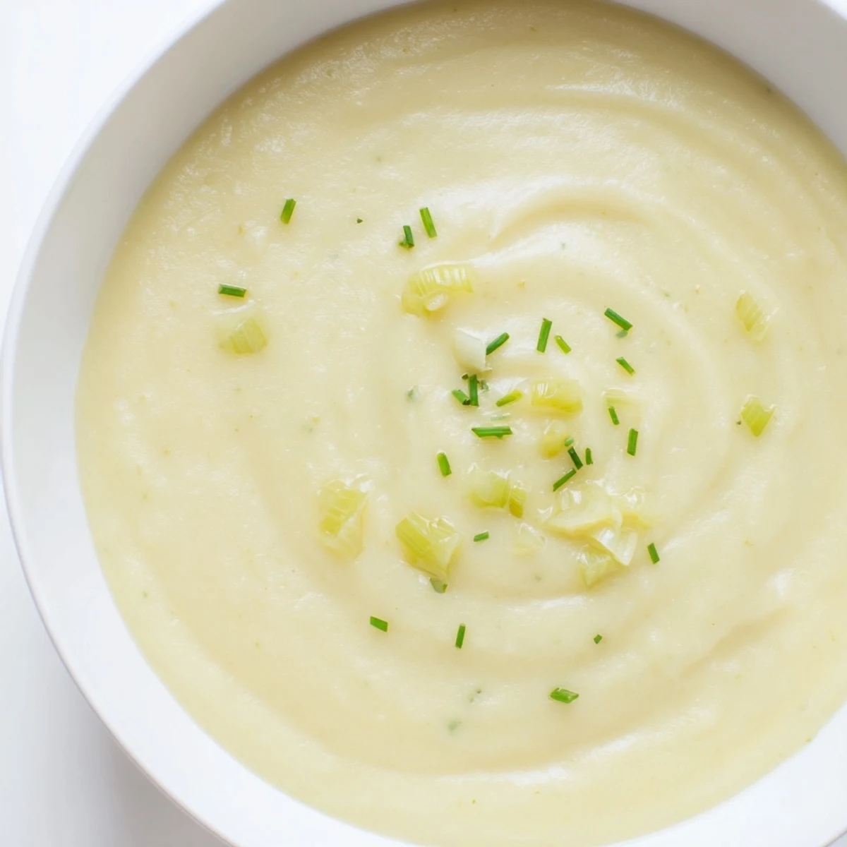 Creamy Potato and Leek Soup steaming in a white bowl, garnished with fresh chives.