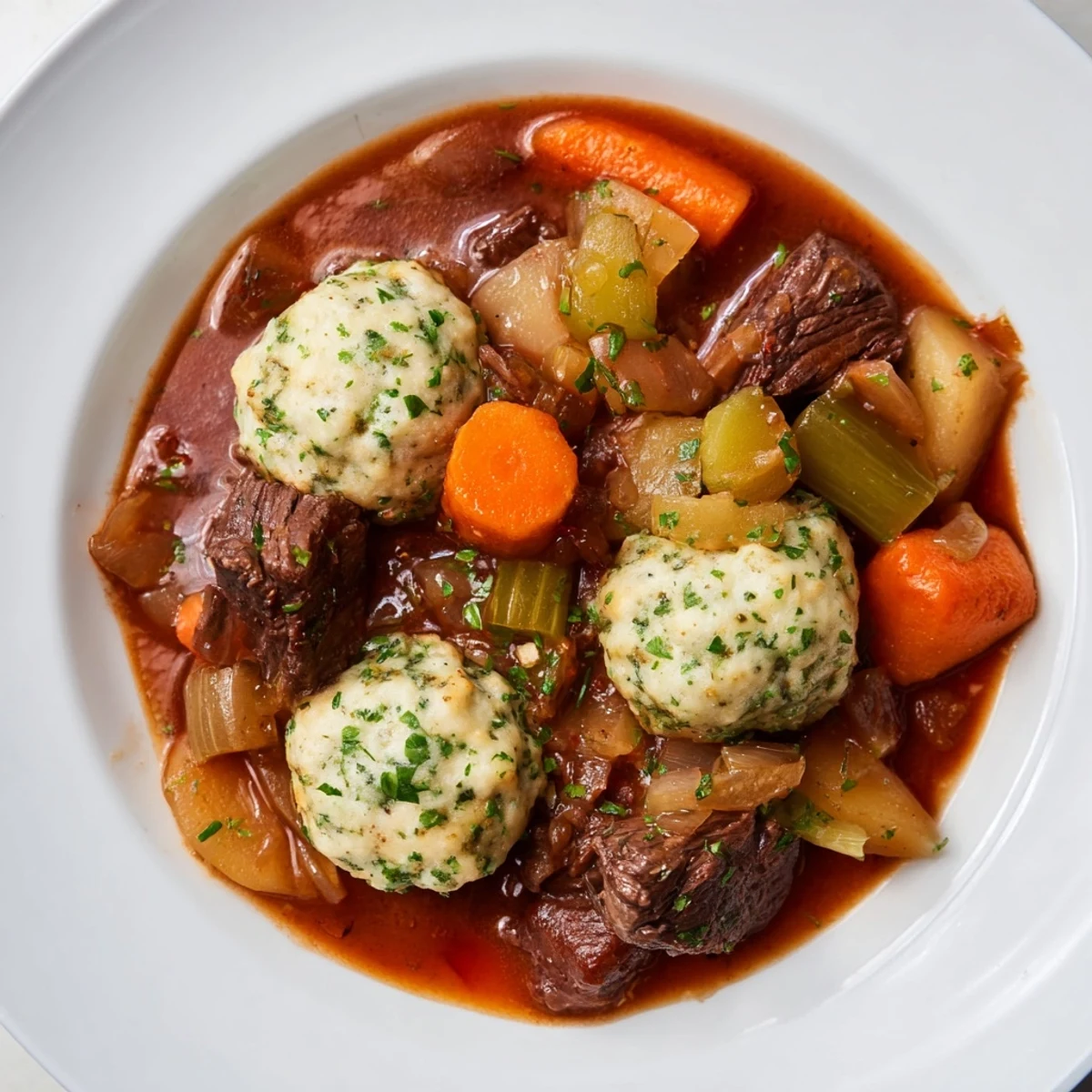 Overhead view of Irish Beef Stew with Herb Dumplings, showing carrots, parsnips, and herb dumplings on top of the stew.