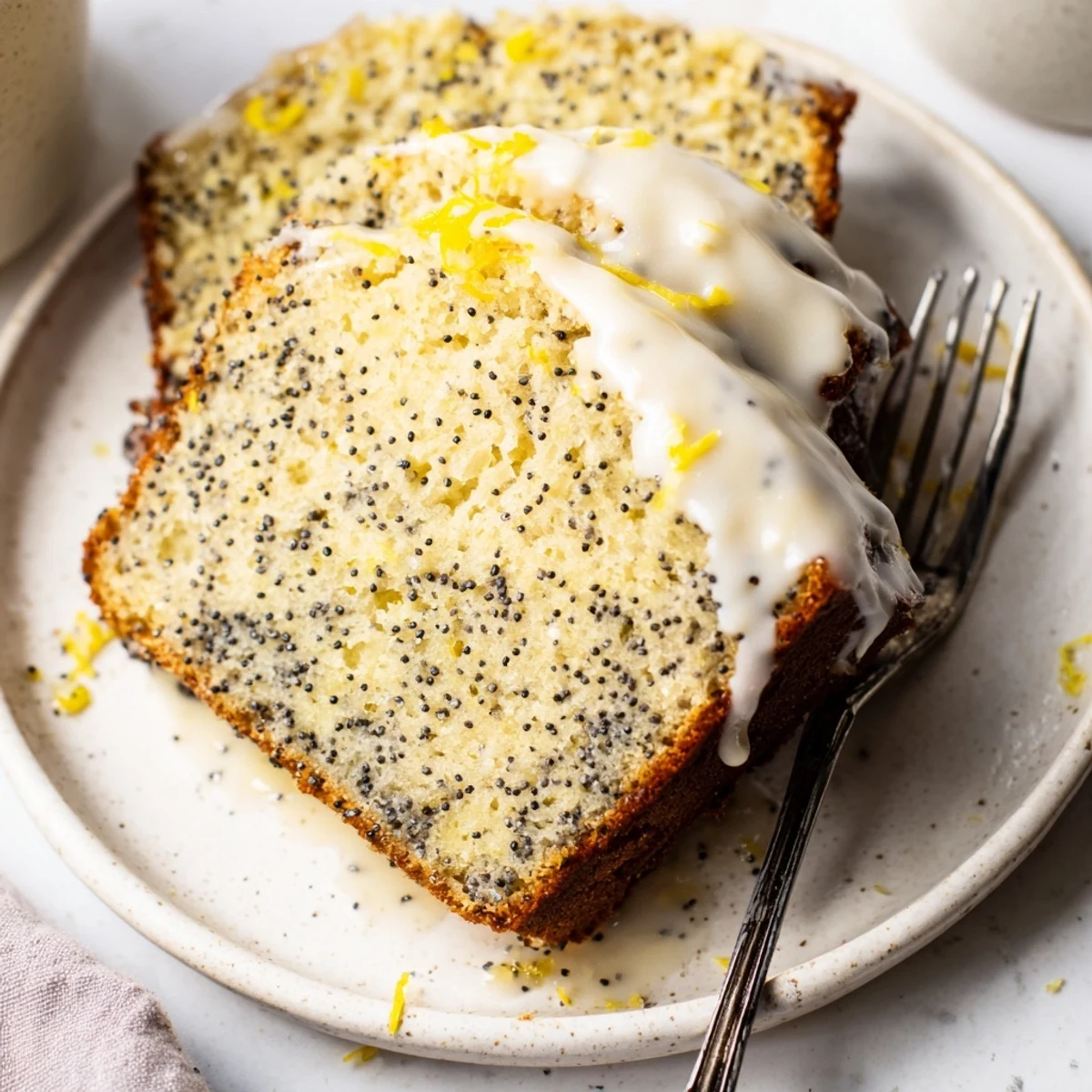 Sunlight highlights the sugary glaze drizzled over a fresh-baked Lemon Poppy Seed Loaf Cake on a marble counter.