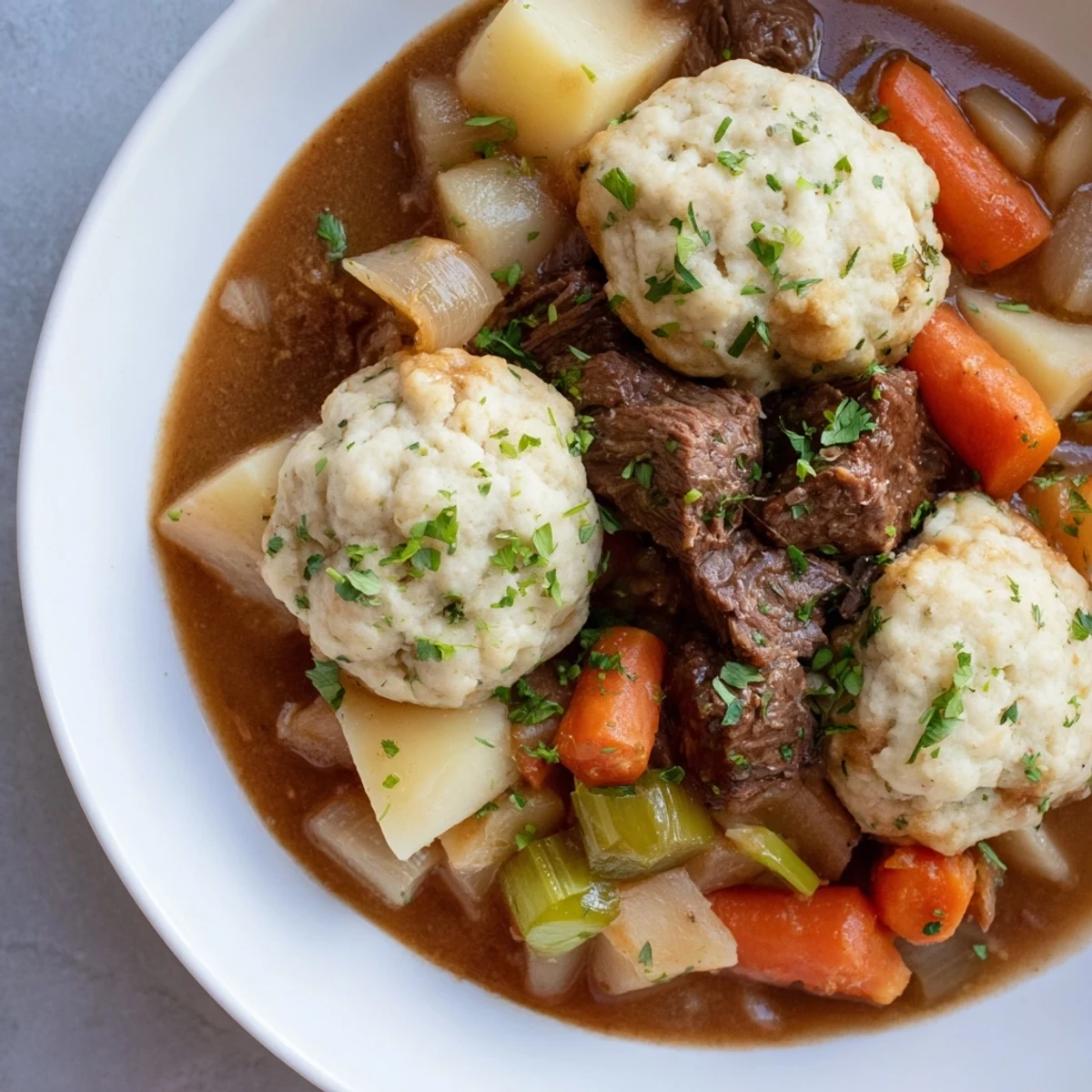 Comforting Irish Beef Stew with Herb Dumplings garnished with fresh parsley on a cozy dinner table.