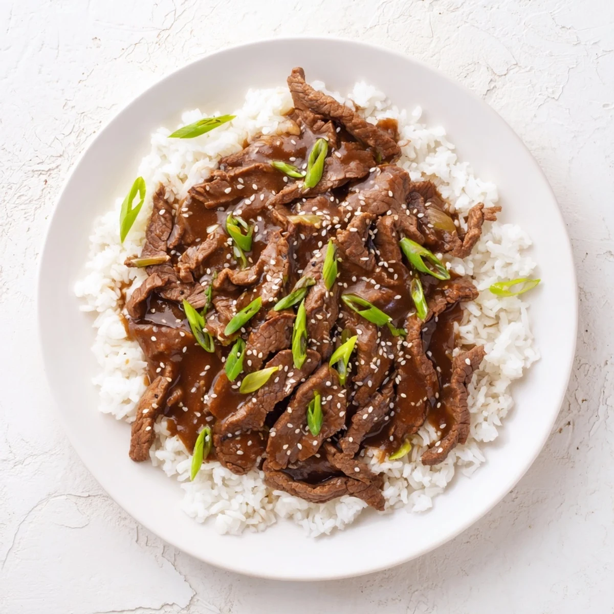 Tender slices of Ultimate Slow Cooker Mongolian Beef simmering in a rich, glossy sauce with aromatics.