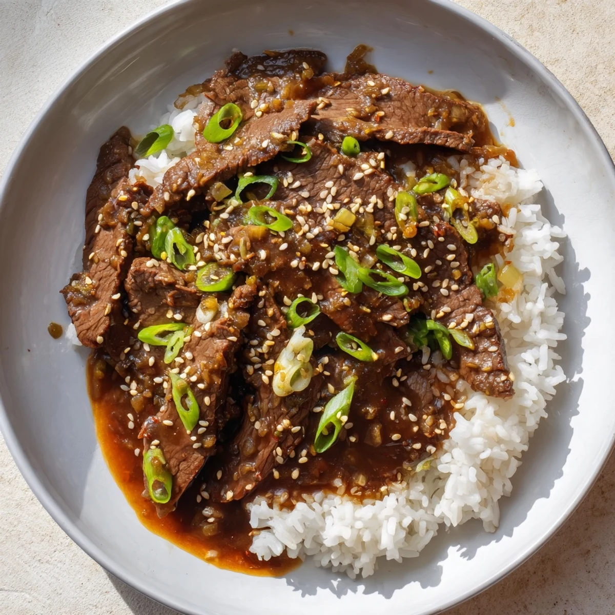 Serving suggestion of Ultimate Slow Cooker Mongolian Beef over fluffy white rice with green onions.