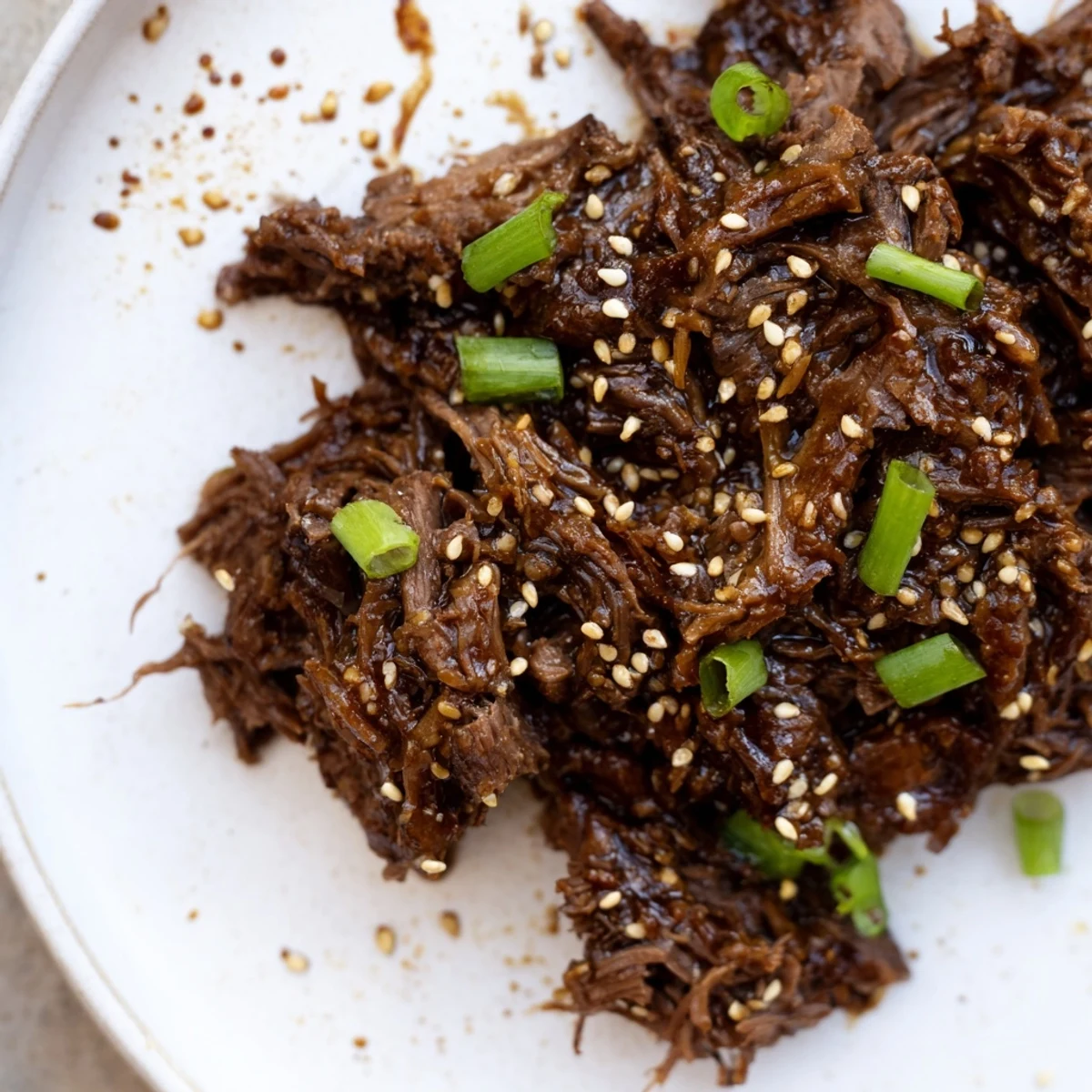 Fork-tender Crock Pot Korean Beef simmered in a glossy, savory-sweet sauce, garnished with green onions and sesame seeds.