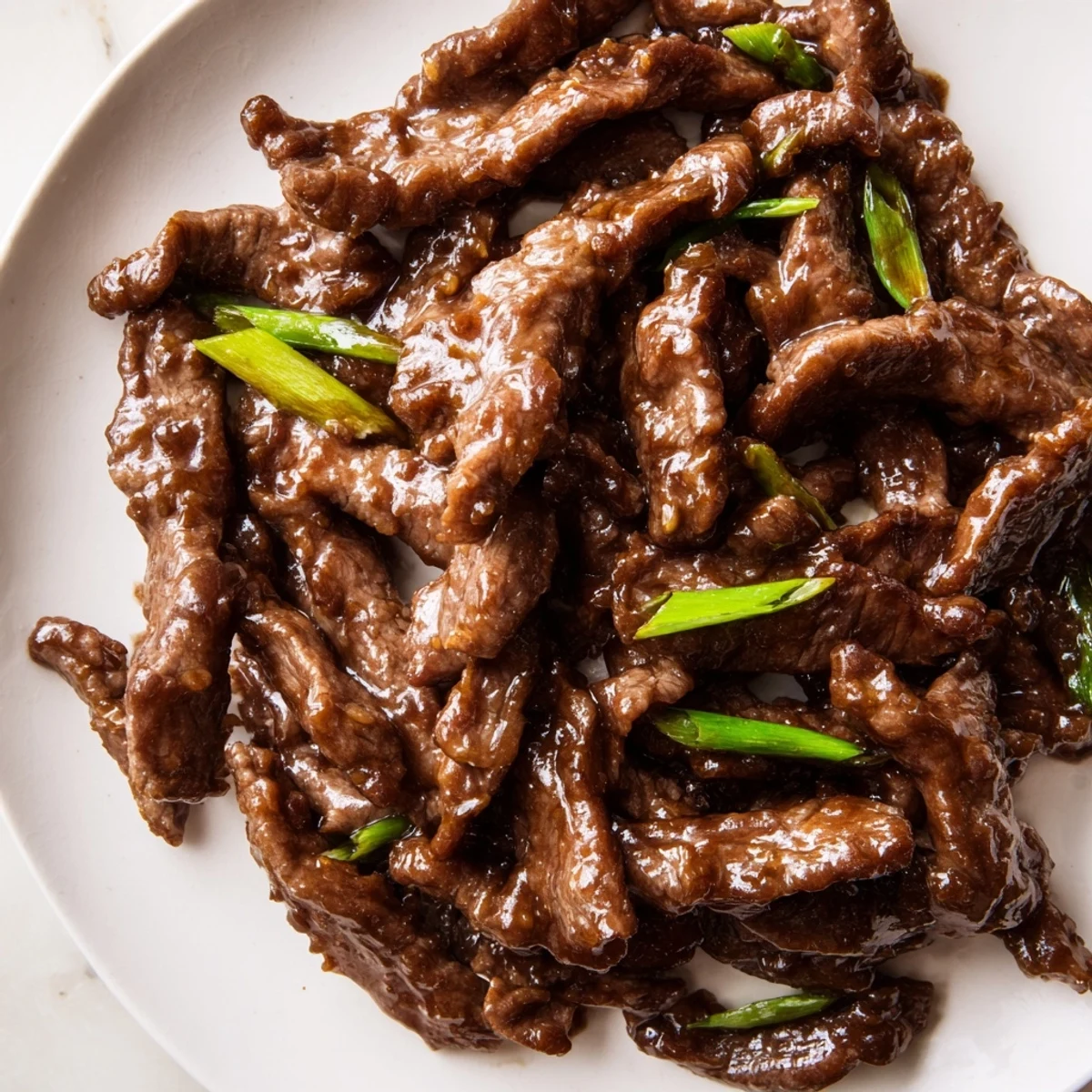 Ultimate Slow Cooker Mongolian Beef simmering in a rich, sweet-savory sauce with garlic and ginger, garnished with sesame seeds and scallions.