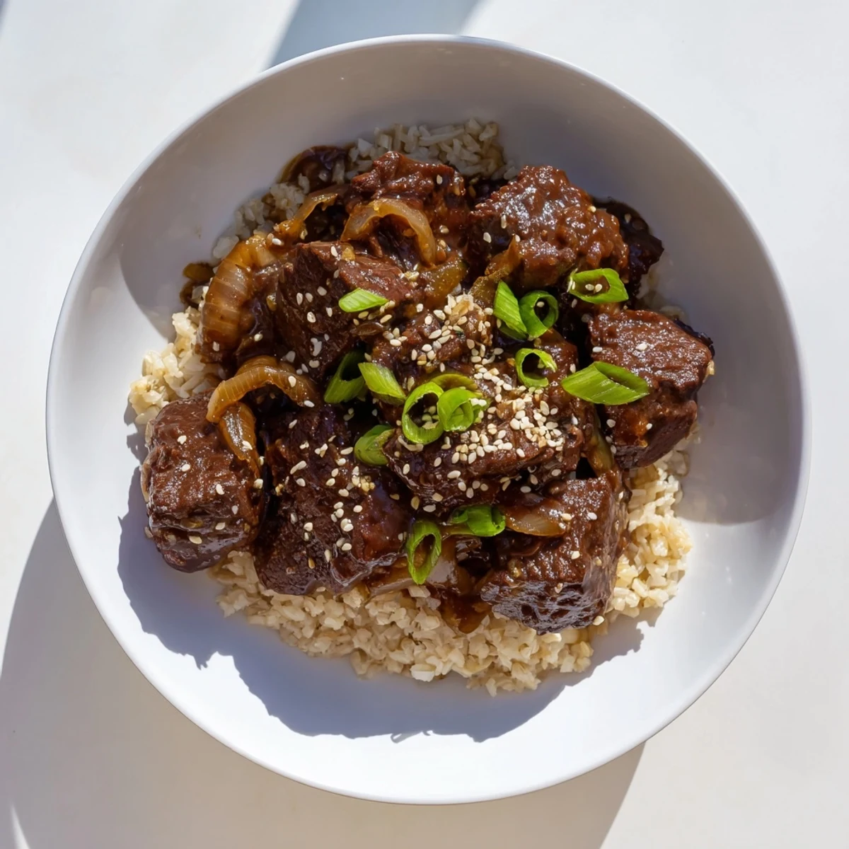 Golden shredded Crock Pot Korean Beef simmering in a savory, spicy sauce, garnished with green onions and sesame seeds.
