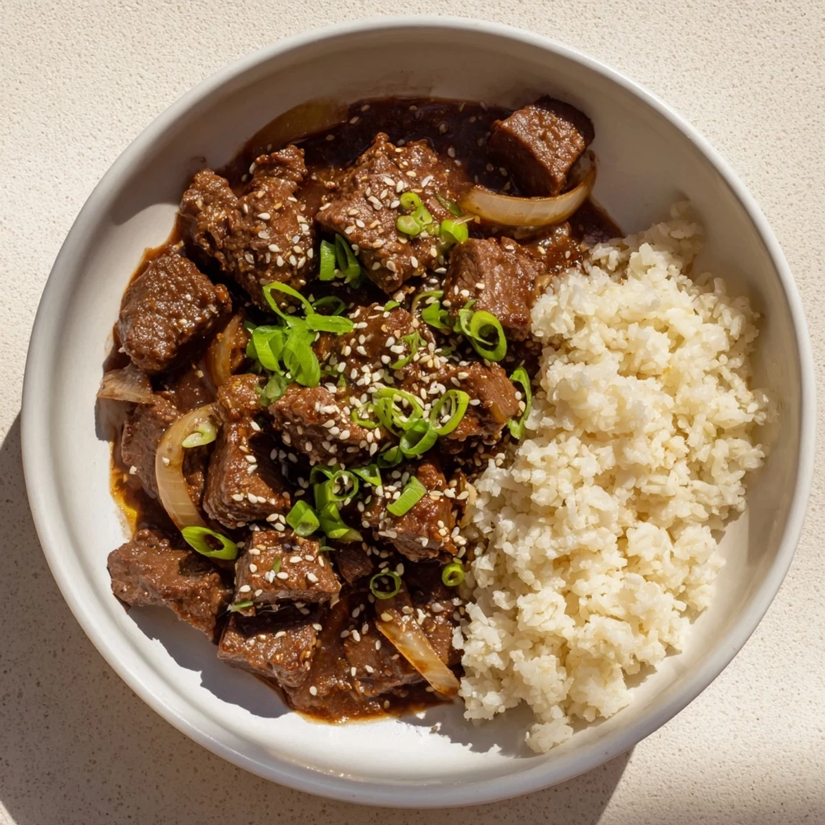 Savory Crock Pot Korean Beef piled high in a bowl, with sesame seeds and fresh scallions for a weeknight meal.