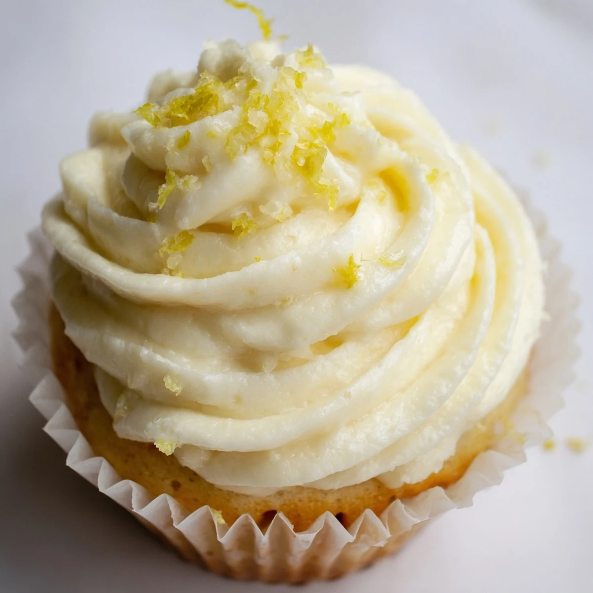Freshly baked elderflower cupcakes on a cooling rack, brushed with syrup and ready to serve with Earl Grey tea for a British-inspired dessert.