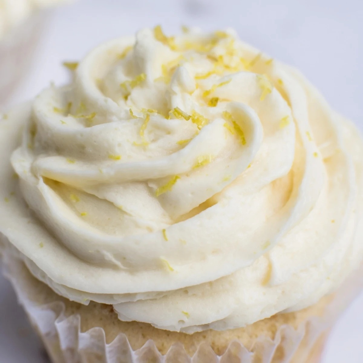 Moist golden cupcakes infused with elderflower cordial, frosted with floral buttercream and a delicate edible flower for an elegant afternoon treat.