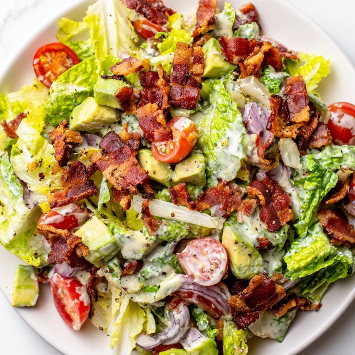 Close-up of Crispy Bacon Keto BLT Salad showing diced avocado, red onion, and crunchy bacon bits.