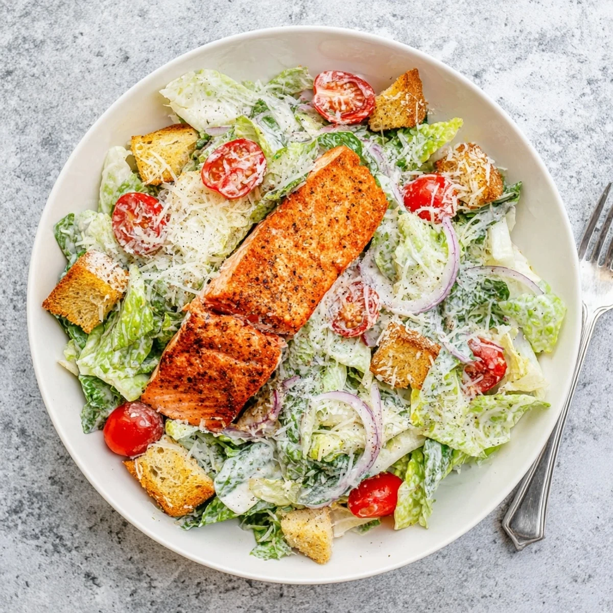 Juicy grilled salmon slices rest on crisp romaine lettuce with creamy dressing and crunchy croutons in this Salmon Caesar Salad.
