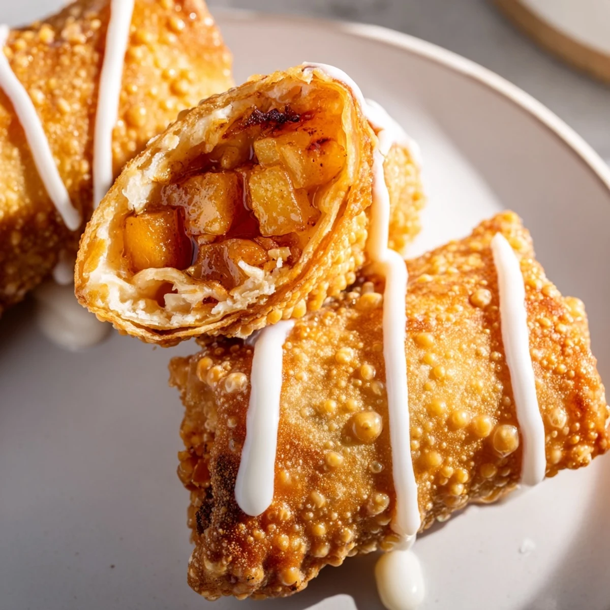 Overhead view of Peach Cobbler Egg Rolls with drizzled vanilla glaze and fresh peaches.  