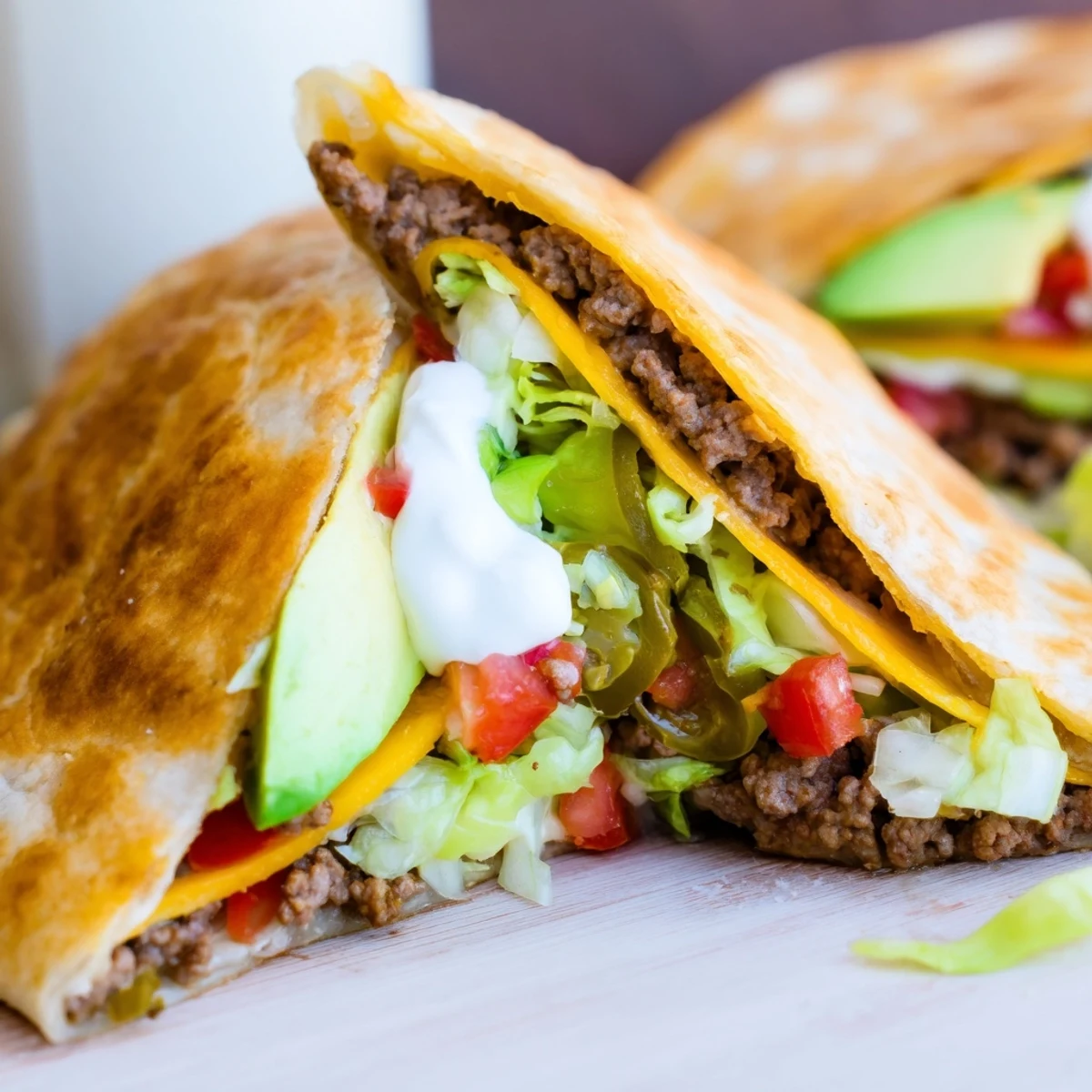 Golden keto crunchwrap with melted cheddar, seasoned beef, fresh lettuce, and tomatoes stacked in layers