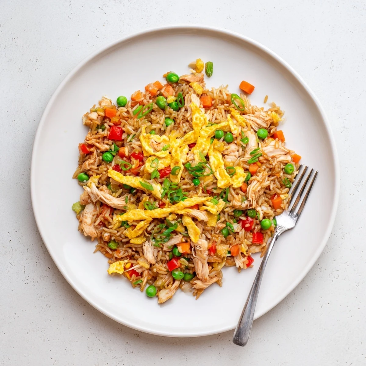 Savory stir-fried chicken fried rice featuring tender meat peas carrots and egg ribbons