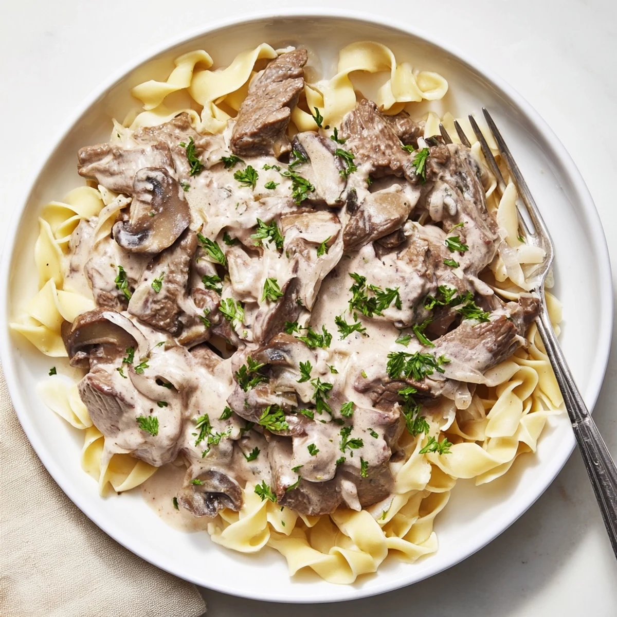 Creamy beef and mushroom stroganoff served over egg noodles with fresh parsley garnish