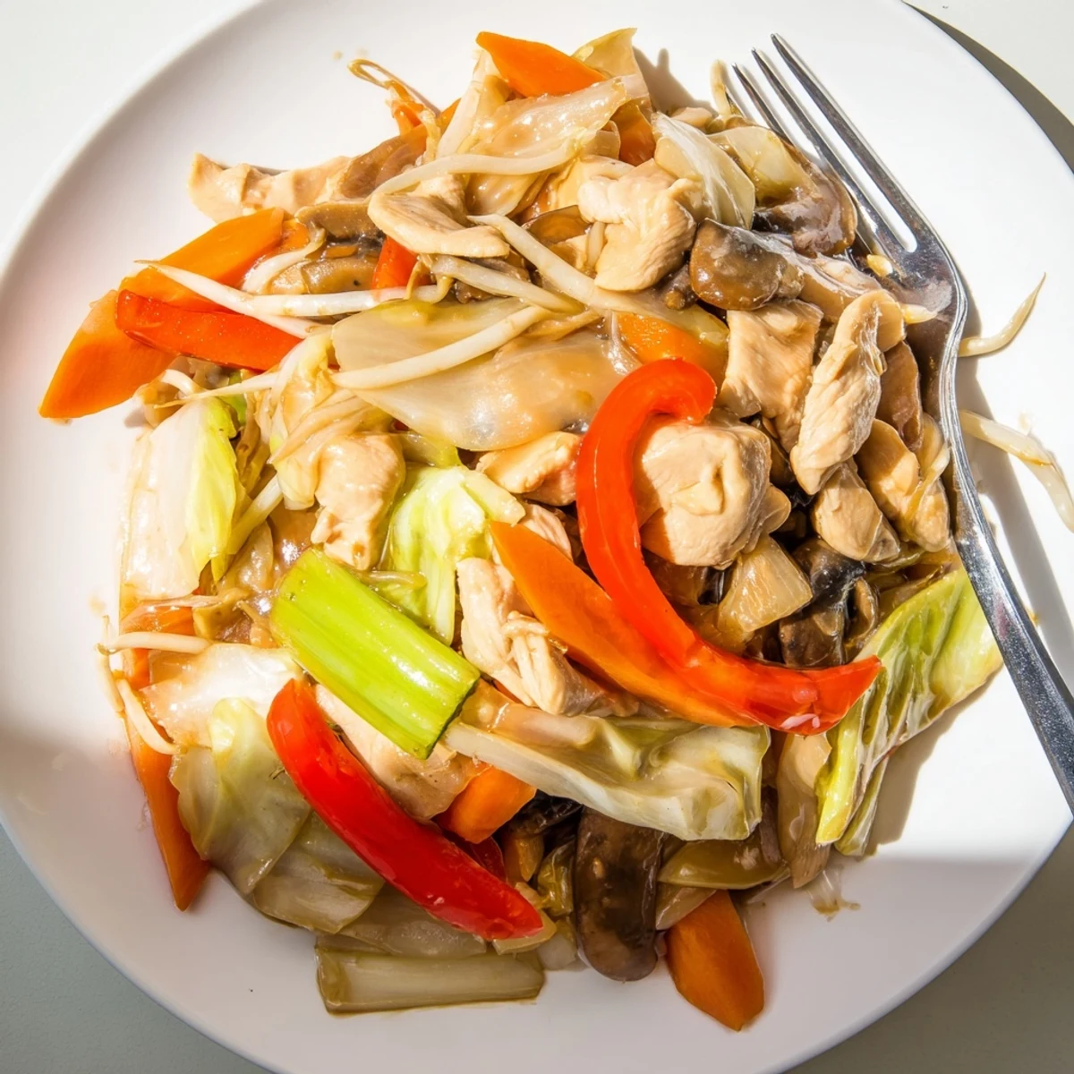 Homemade Chop Suey brimming with crunchy celery, carrots, mushrooms, and protein in a savory sesame-soy glaze on a dinner plate