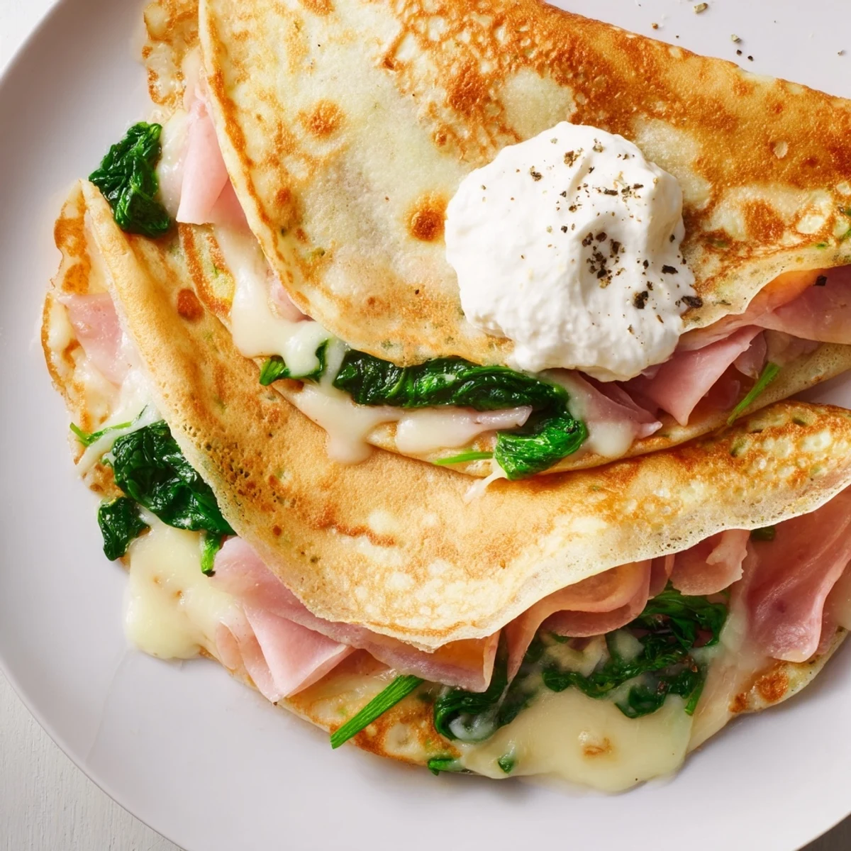 Savory crepes recipe featuring warm, tender crepes stuffed with ham and bubbling cheese topping