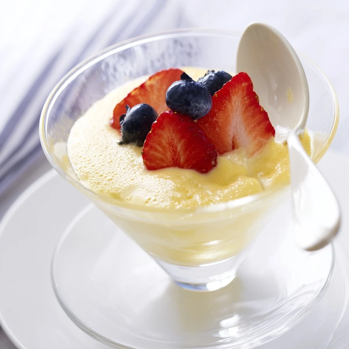 Golden Italian Zabaglione custard served warm in elegant glass bowls with fresh berries