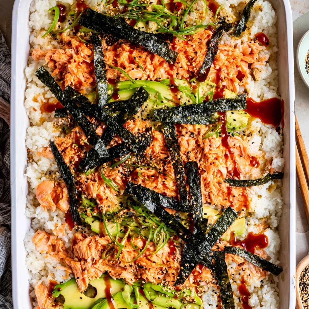 Creamy salmon sushi bake layered over vinegar rice, garnished with furikake and ripe avocado
