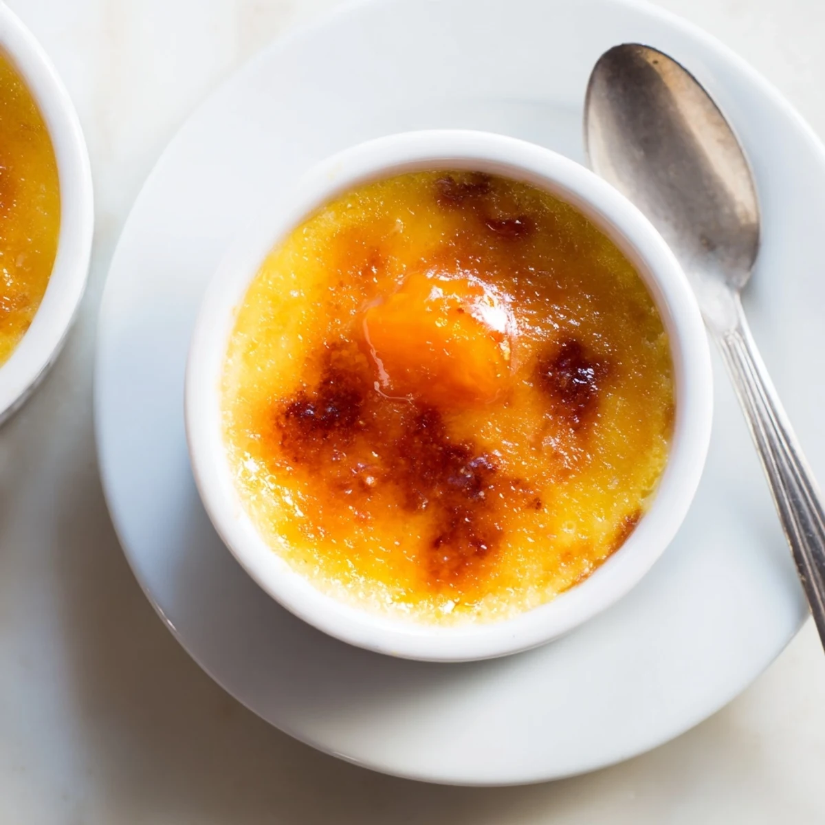 Silky orange persimmon custard beneath cracked burnt sugar topping in individual serving dish