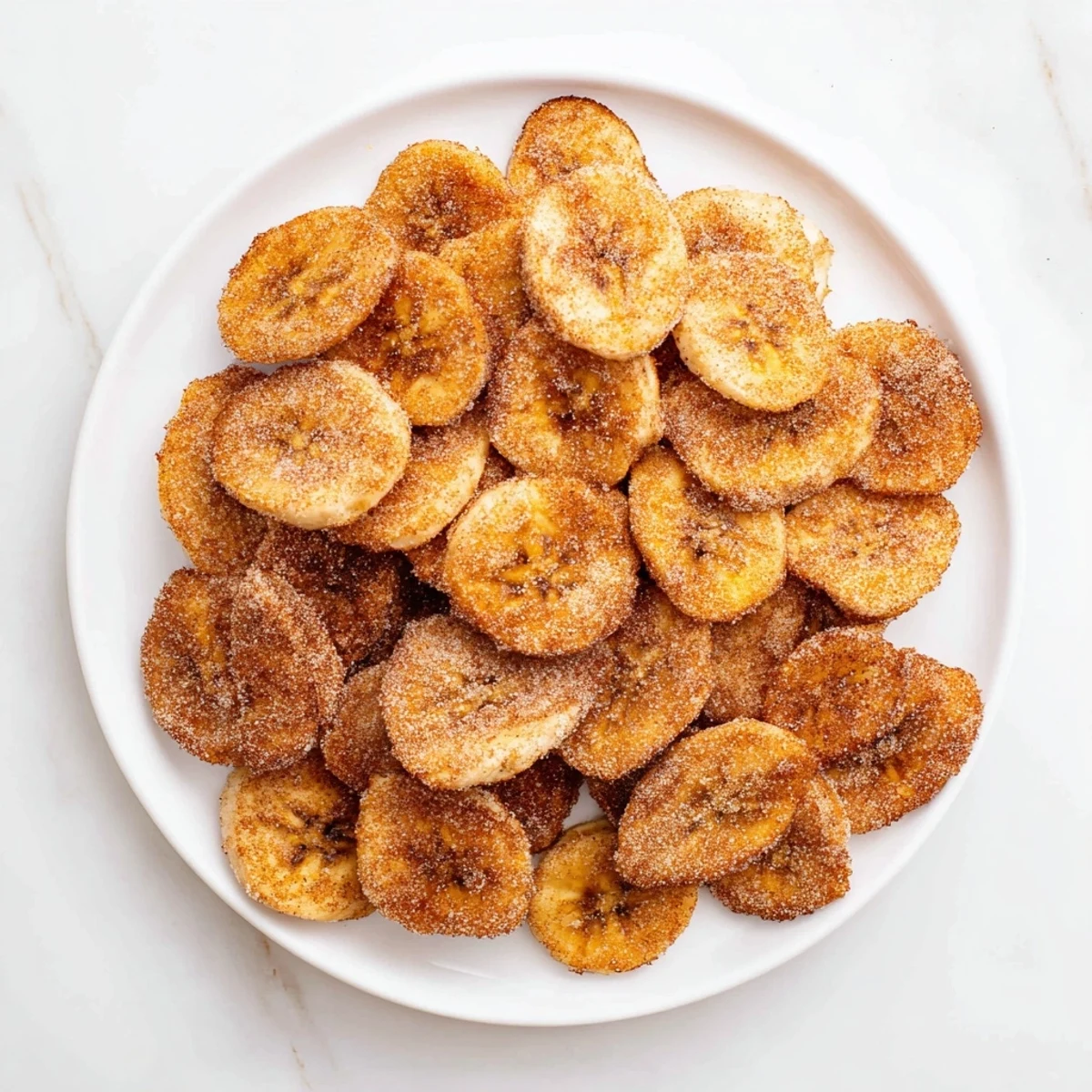 Homemade air fryer banana chips sprinkled with cinnamon sugar for a healthy snack
