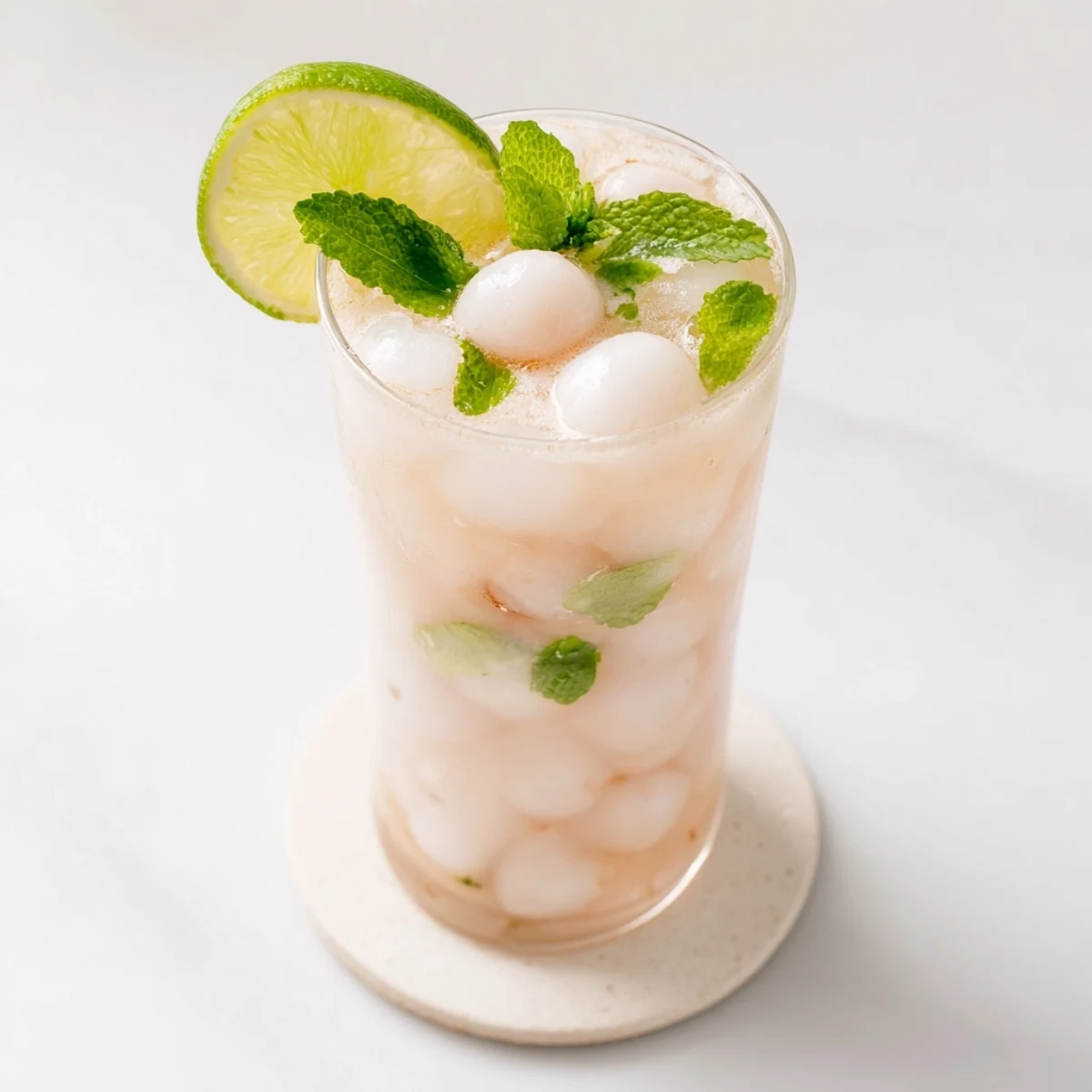 Creamy white coconut lychee iced drink topped with whole lychee fruit in a chilled clear glass