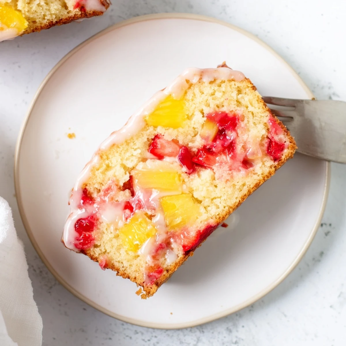 Golden slice of strawberry pineapple pound cake topped with sweet glazed pineapple chunks