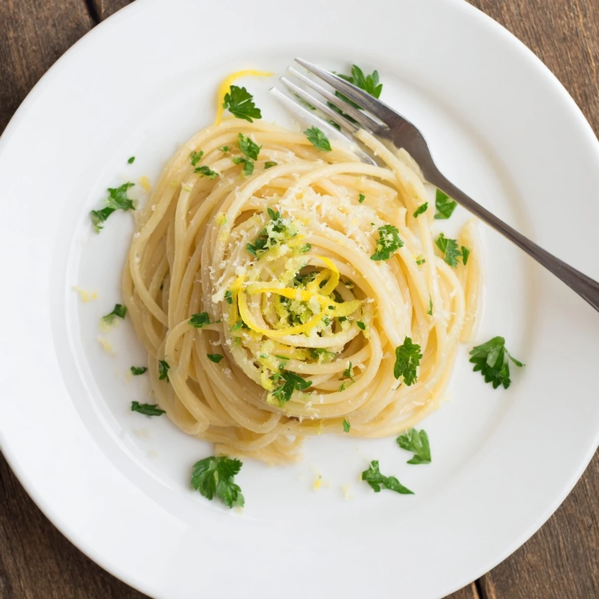 Golden spaghetti coated in garlic butter sauce with lemon zest and chopped herbs for easy weeknight dinners