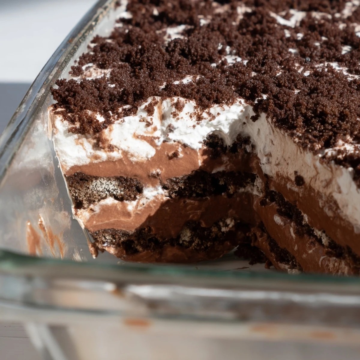 Glass trifle dish showcasing layered keto dirt cake with chocolate crumbs and whipped cream