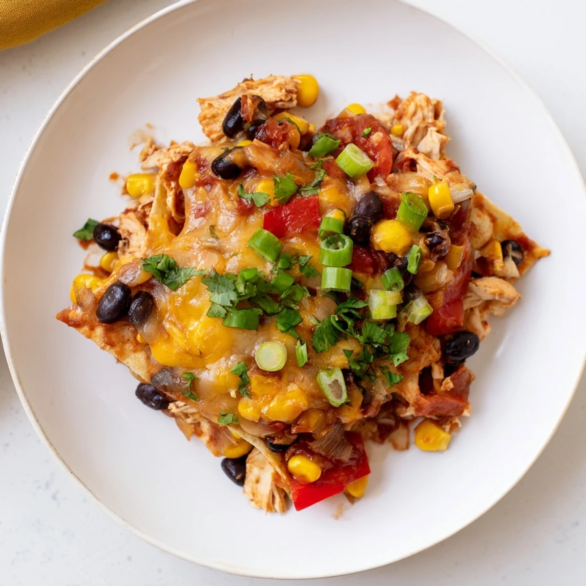 Golden corn tortilla layered chicken enchilada casserole served with sour cream and green onions