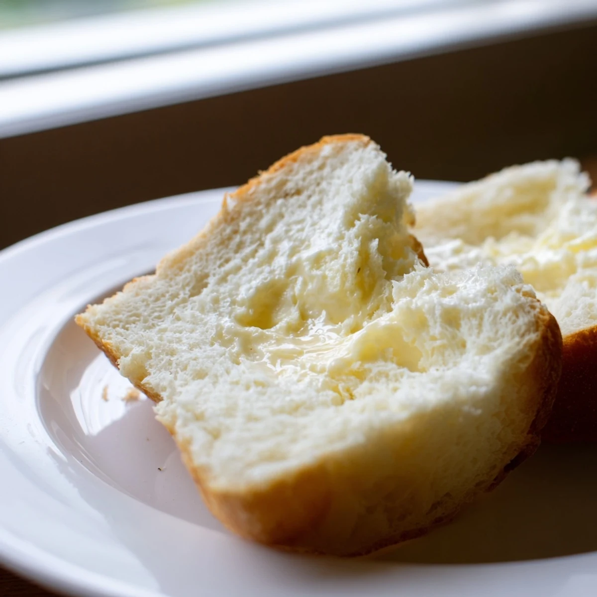 Two perfectly risen homemade Amish white bread loaves brushed with melted butter and ready for slicing