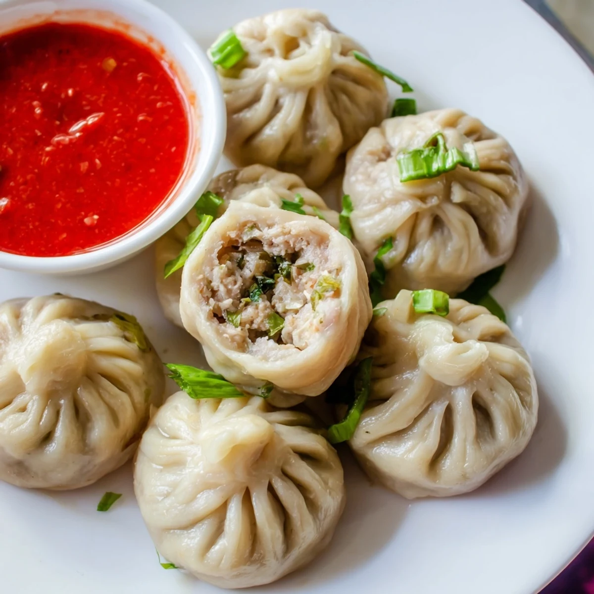 Golden steamer basket filled with freshly made Nepali momo dumplings garnished with fresh cilantro