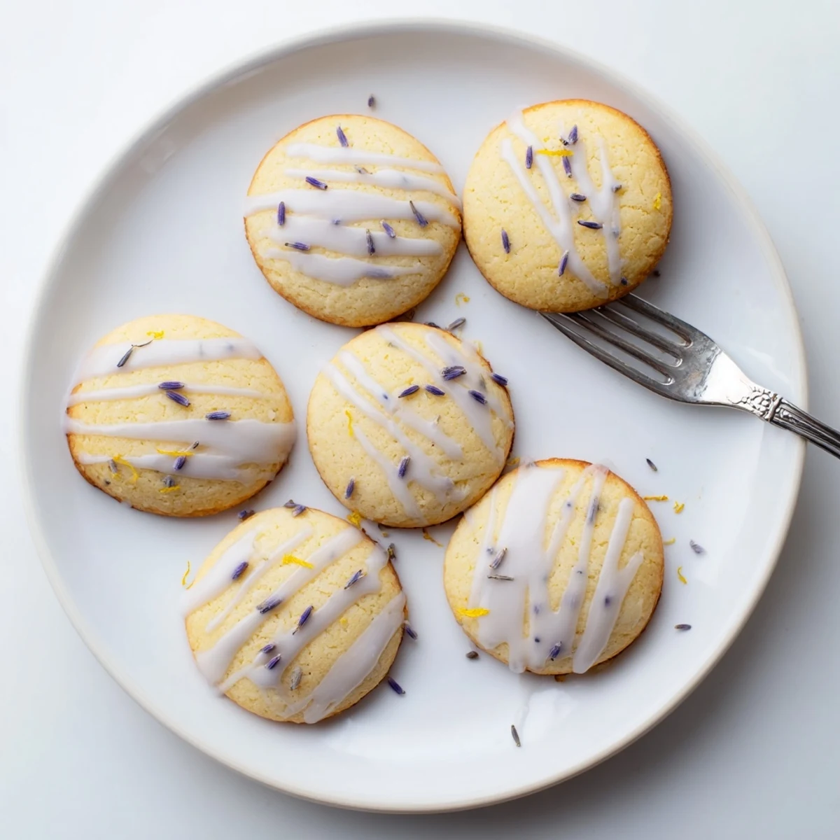 Soft lemon lavender cookies with golden edges arranged on a rustic white ceramic plate