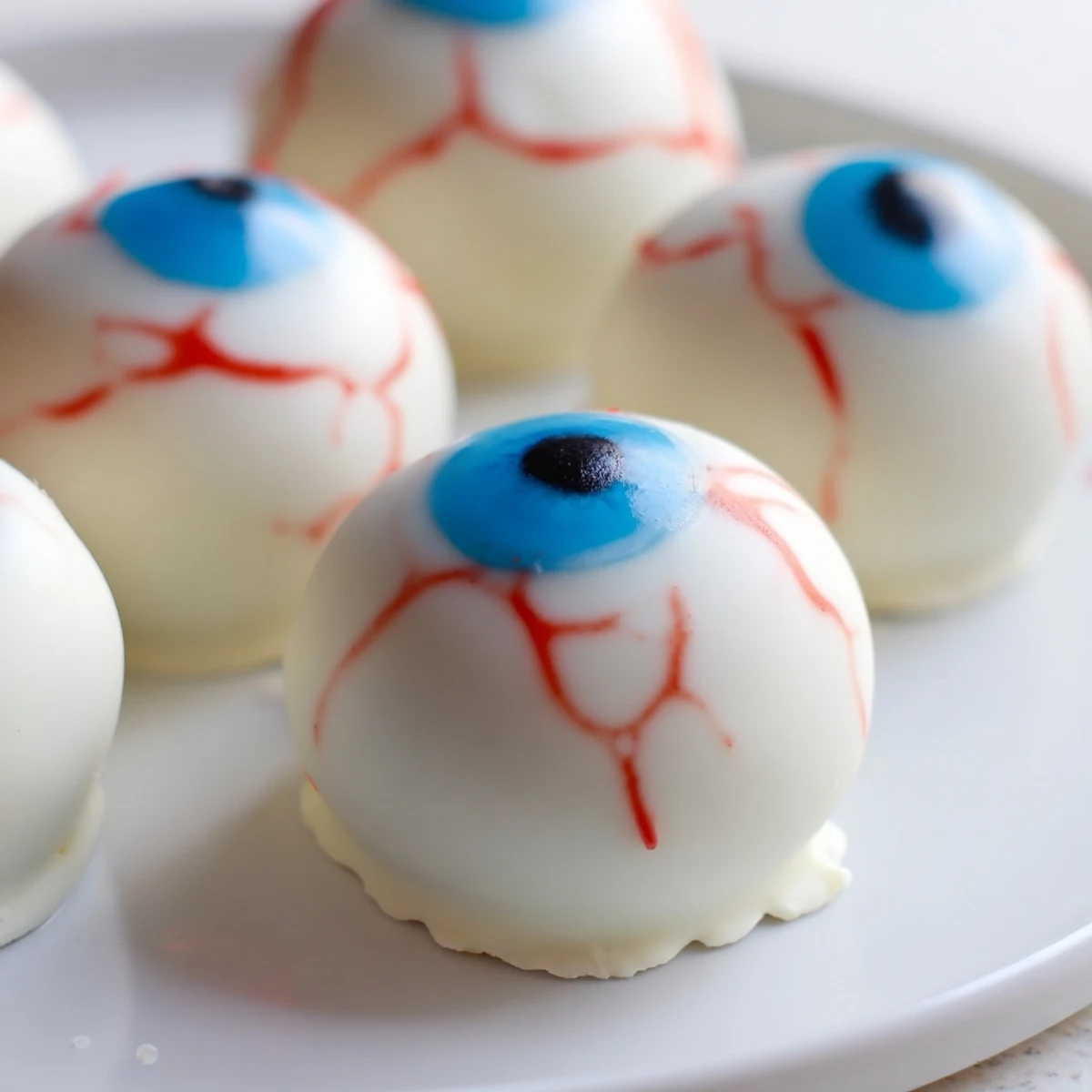 Halloween Cake Eyeballs with creamy frosting, chocolate coating, and spooky red veins on a party platter