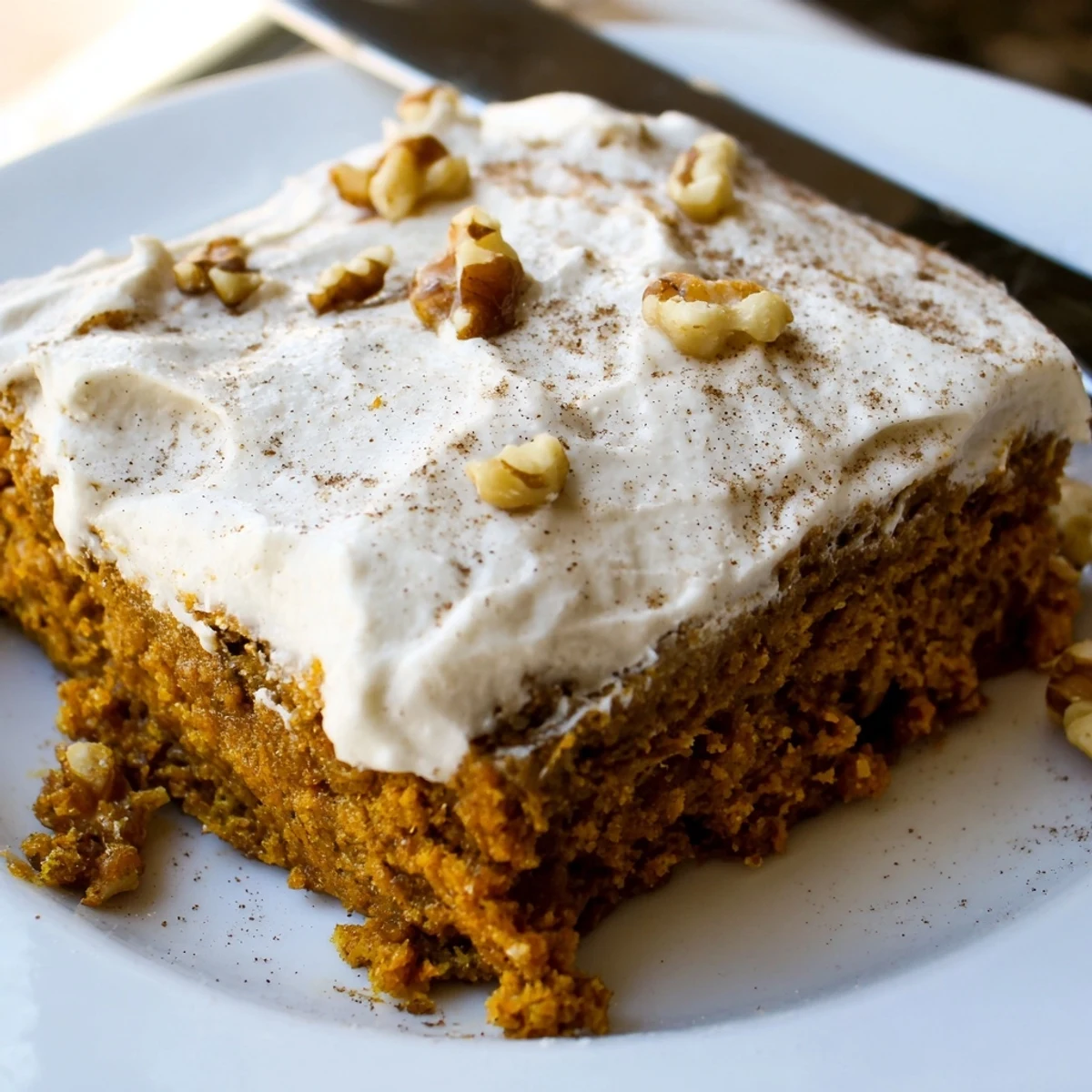 Golden pumpkin bars with cream cheese frosting arranged on a white serving platter for fall