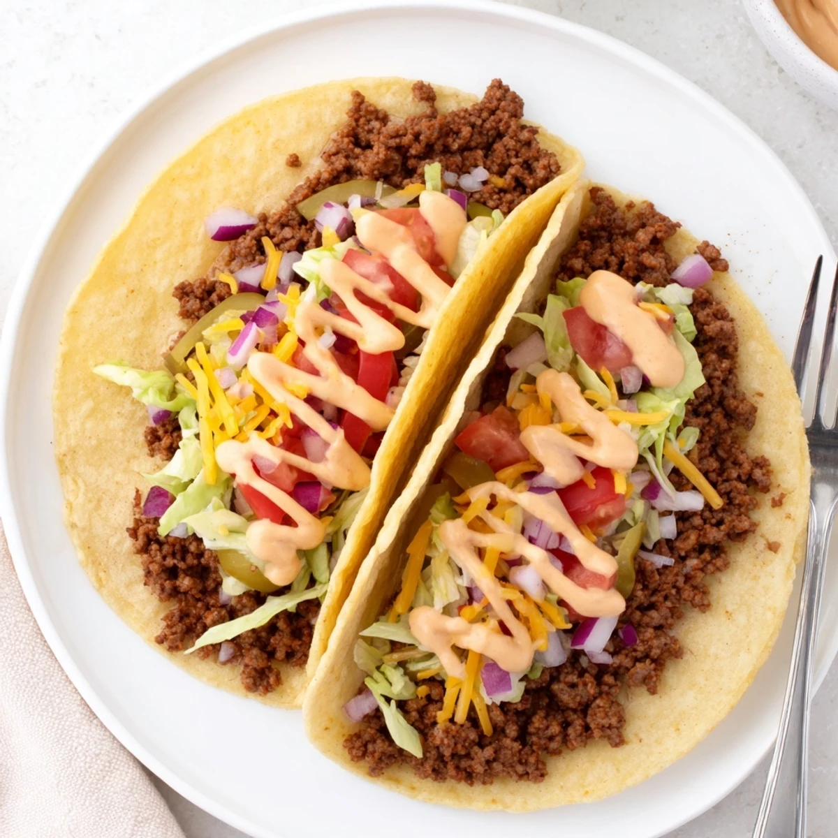 Golden tortilla smash burger tacos drizzled with creamy burger sauce