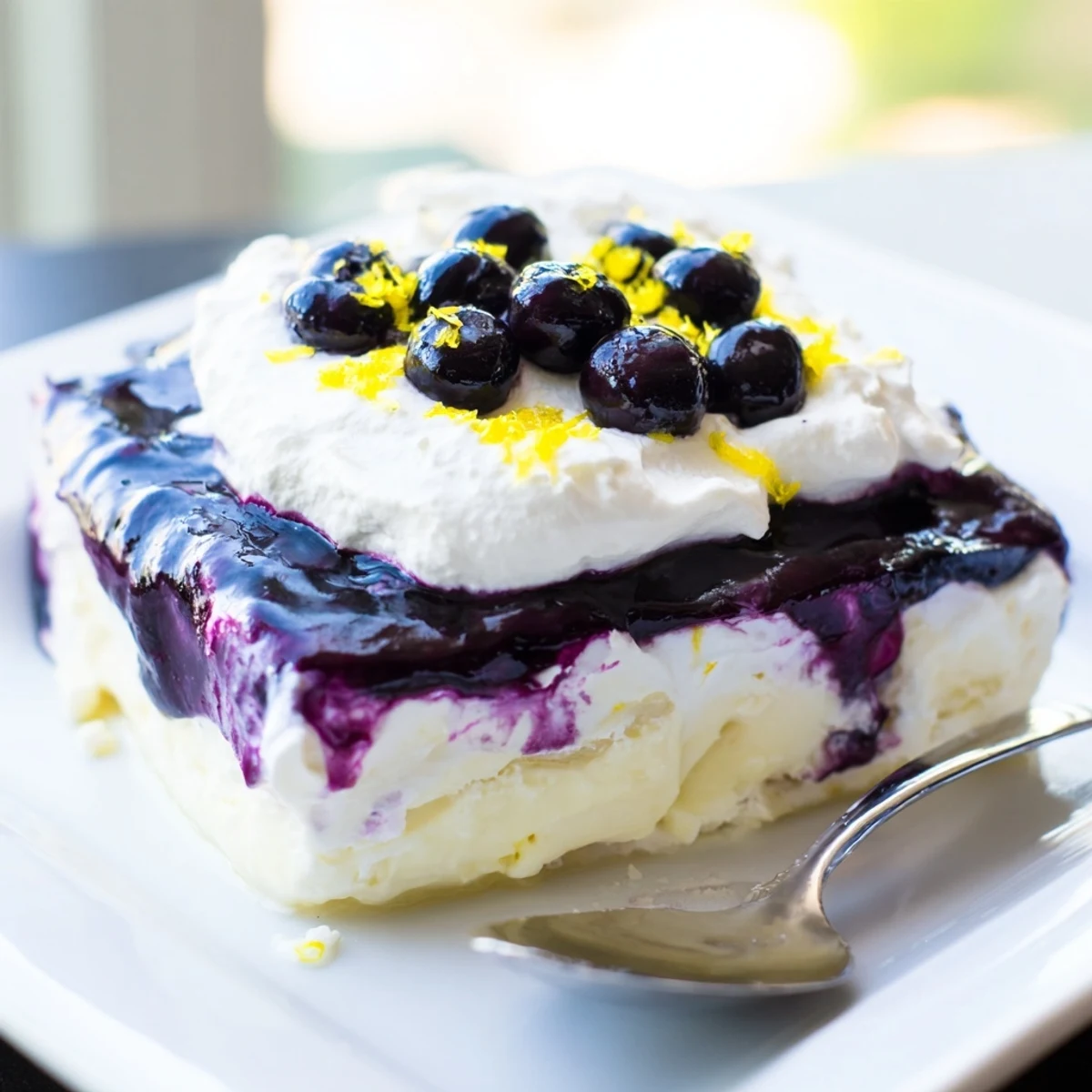No-bake lemon blueberry lasagna recipe sliced into squares topped with fresh berries