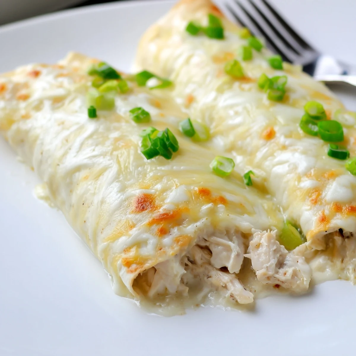 Creamy White Chicken Enchiladas bubbling golden, garnished with cilantro and green onions