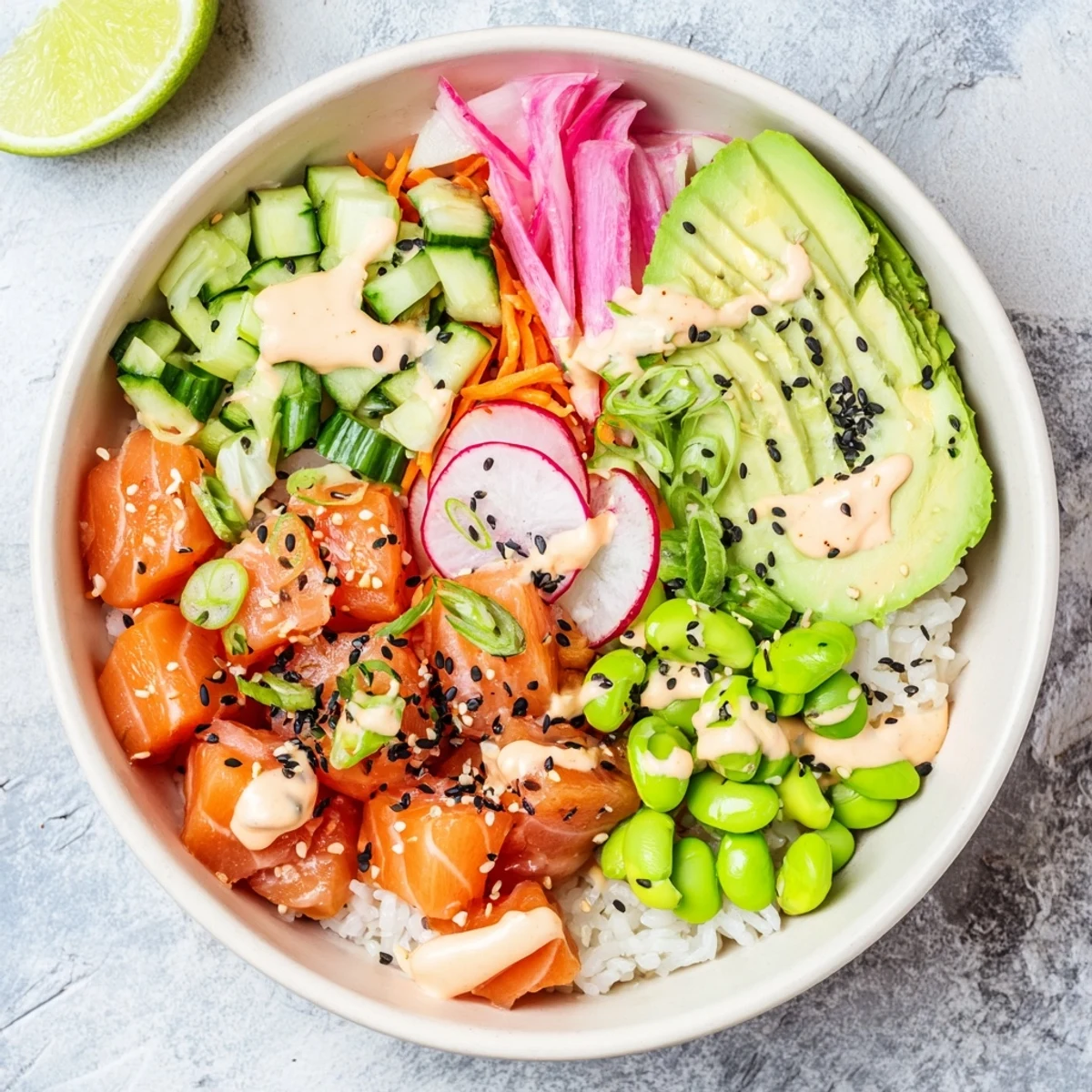 Fresh salmon and avocado poke bowl arranged in layers with cucumber, radish, edamame, and creamy spicy mayo