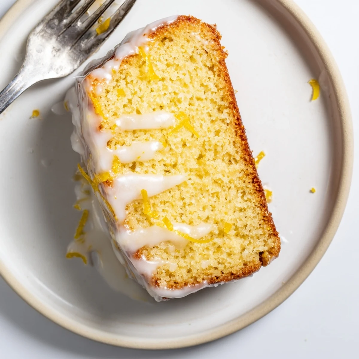 Moist lemon glazed loaf cake slice showing tender crumb on a white plate