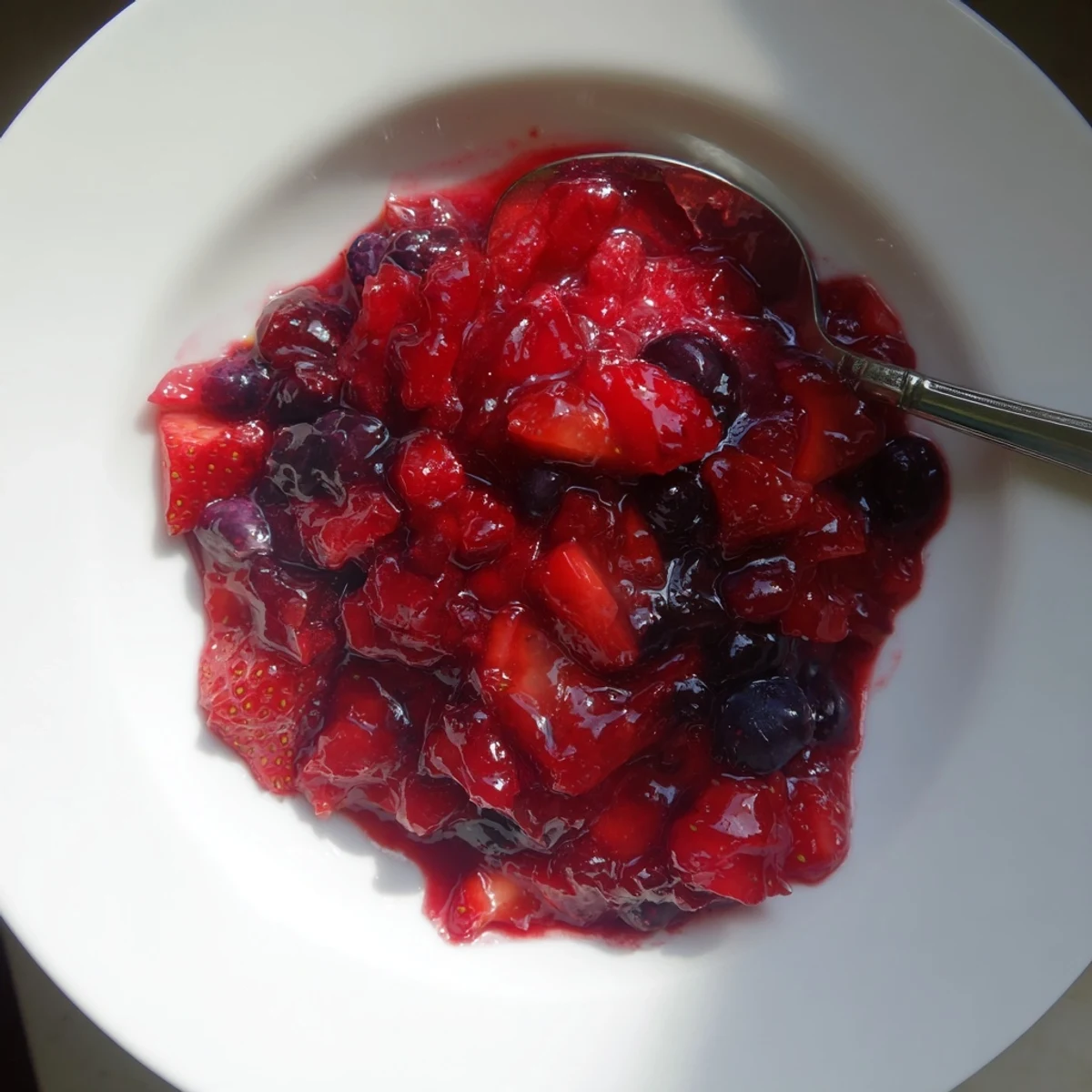 Golden jar of strawberry rhubarb raspberry jam with berry twist spread on buttered toast